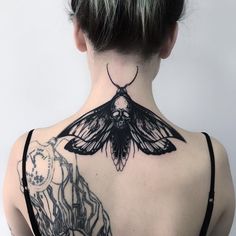 the back of a woman's neck with a moth tattoo on it