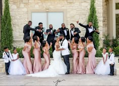 a group of people standing around each other in front of a building with their arms up