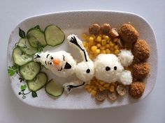 a white plate topped with rice and veggies next to cucumber slices