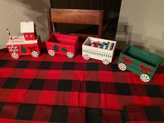 the table is covered with red and black checkered cloth, boxes containing christmas decorations