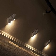 three lights that are on the side of a wall next to a carpeted floor