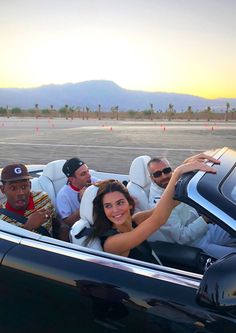 a group of people riding in the back of a convertible car