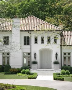 The front exterior of a white house with orange spanish tile shingles and a beautifully manicured green lush lawn Terracotta Roof House Exterior Colors Spanish, Meditteranean Style Home Exterior, Houses With Tile Roofs, House With Spanish Tile Roof, Updated Mediterranean Home Exterior, Terracotta Tile Roof House Exterior Colors, Exterior House Colors With Spanish Tile Roof, Spanish Tile House Exterior, Gray Mediterranean House Exterior