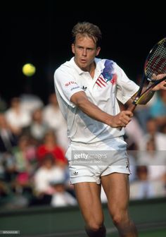 a tennis player swinging his racket at the ball during a match in front of an audience