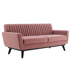 a pink velvet sofa with black legs and an arm that is bent to the side