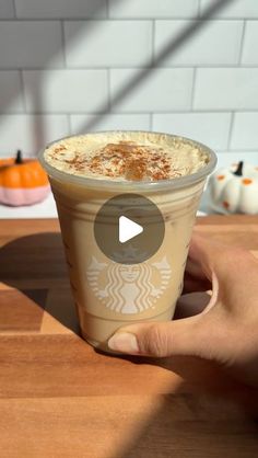 someone holding up a cup of coffee with whipped cream in it