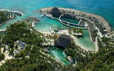 an aerial view of a resort in the middle of the ocean with trees surrounding it