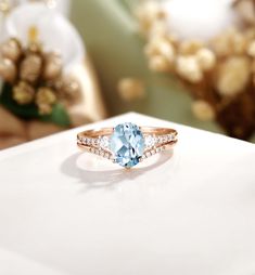 a ring with an oval blue topaz surrounded by small white diamonds on a table