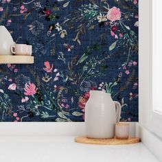 a vase sitting on top of a counter next to a wallpaper covered in flowers