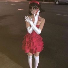 a woman dressed in costume poses on the street with her hands up to her face