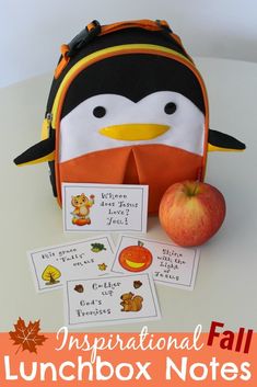 an orange and black lunchbox with penguin on it, next to some cards that read inspirational fall lunchbox notes