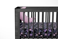 a baby crib with a black and purple floral bed spread on top of it