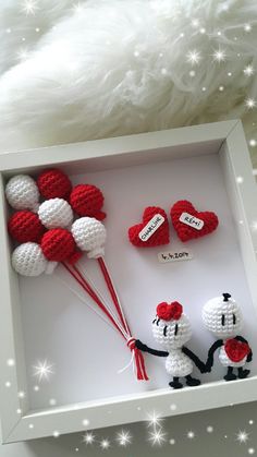 two crocheted red and white balloons are in a shadow box with hearts on them