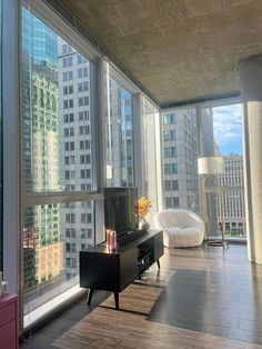 a living room filled with furniture and large windows overlooking the cityscape in the background