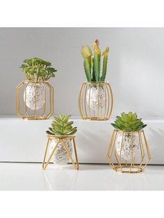 three gold planters with succulents in them on a white countertop