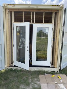 an open white door sitting in the back of a shipping container that is being built