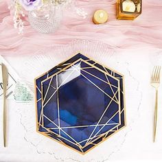 the table is set with gold and blue plates, silverware, napkins, and flowers