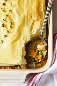 a casserole dish with peas, carrots and other food items in it