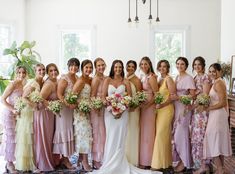 a group of women standing next to each other wearing dresses and holding bouquets in their hands