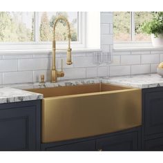 a kitchen with marble counter tops and gold sink faucet in front of the window