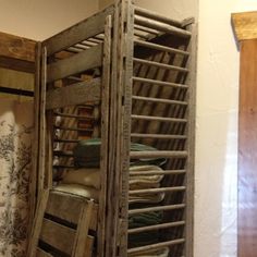 an old wooden storage rack filled with folded linens and other items in a room