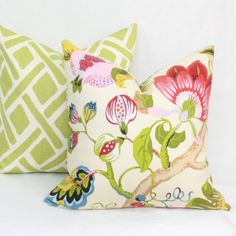 two decorative pillows are sitting side by side on a white surface, one is green and the other is red