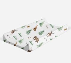 a baby changing pad with animals and trees printed on the front, along with white background