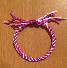 a pink and white bracelet on top of a wooden table