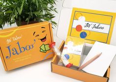 an open box with various items in it sitting on a table next to a potted plant