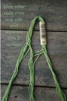 a piece of green string sitting on top of a wooden floor next to a needle