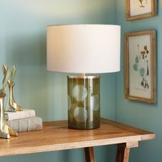 a lamp sitting on top of a wooden table next to a book and some pictures