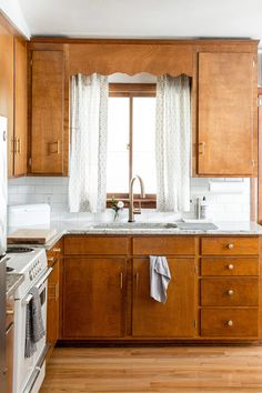 a kitchen with wooden cabinets, white appliances and a window over the sink is shown