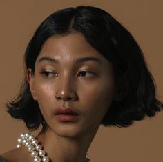 a close up of a woman wearing a pearl necklace