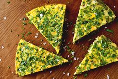 four slices of quiche on a wooden cutting board with chopped parmesan cheese and chives