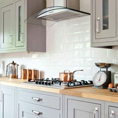 a kitchen with white cabinets and stainless steel stove top hood over the range in front of an oven