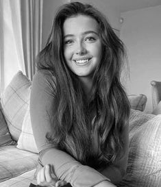 a black and white photo of a woman sitting on a couch holding a remote control