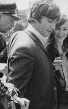 black and white photograph of two people standing next to each other with police in the background