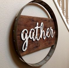 a wooden sign that says gather hanging on the wall next to a spiral stair case