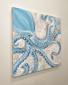 an octopus painting hanging on the wall next to a white wall with blue and beige swirls