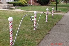 some white and red striped poles on the side of a sidewalk in front of a house