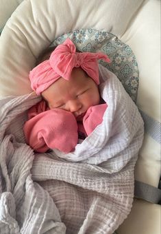 a newborn baby wrapped in a blanket and wearing a pink headband