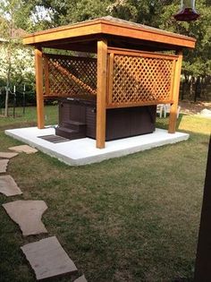 a wooden gazebo sitting on top of a lush green field next to a stone path