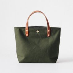 The Green Canvas mini tote is a canvas and leather tote handmade in the KMM & Co. studio in Atlanta. Each one is meticulously crafted from heavyweight canvas and gorgeous full-grain leather. Green Canvas is a type of cotton canvas known as duck cloth. It's one of the most durable types of cloth, and it's structured enough to stand up on its own. The Green Canvas mini tote comes standard with Tan handles. Canvas Bag With Rolled Handles For Everyday Use, Everyday Canvas Shoulder Bag With Rolled Handles, Everyday Canvas Bag With Rolled Handles, Green Waxed Canvas Bag, Duck Cloth, D Rings, Mini Tote, Full Grain Leather, Leather Tote