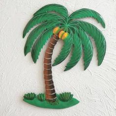 a paper cut palm tree with yellow and green fruit on it's leaves, hanging from a white wall