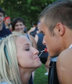 a man and woman kissing each other in front of a group of people on the grass