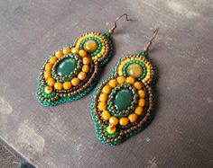 two pairs of beaded earrings with green and yellow beads on top of a piece of fabric