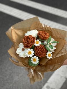 a person holding a bouquet of flowers in their hand on the street with a crosswalk in the background