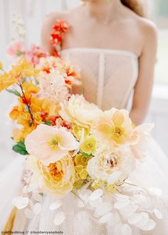 a woman in a white dress holding a bouquet of orange and yellow flowers on her wedding day