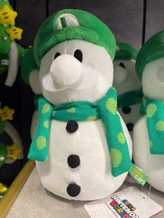 two snowmen with green hats and scarves on their heads sitting next to each other