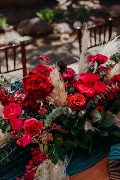 a bouquet of red roses and feathers on a table